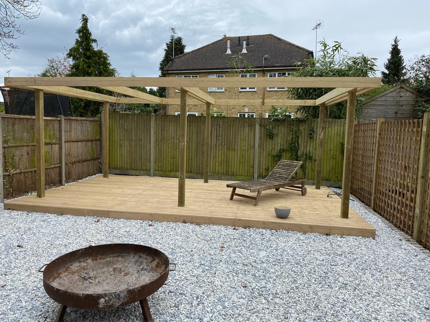 Timber pergola over garden decking, with trellis screening alongside.