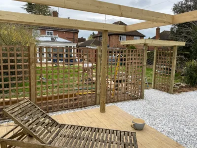 Garden decking with trellis screening beneath a timber pergola.
