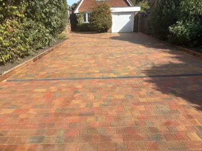 Red and buff block-paved driveway with a drainage channel and brick edging.
